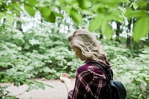 Portrait of an attractive blond girl posing with a compass in a forest. photo