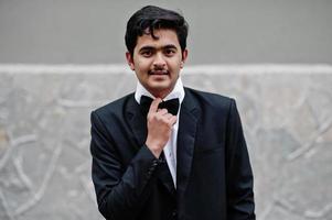 Young indian man on black suit and bow tie posed outdoor. photo