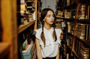 Girl with pigtails in white blouse at old library. photo