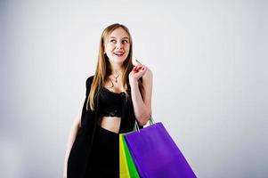 Girl model in black wear with colored shopping bags posed at studio on white background. photo