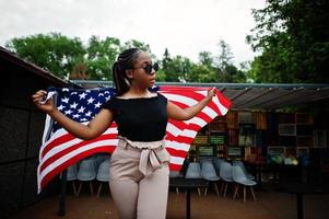 Stylish african american woman in sunglasses posed outdoor with usa flag. photo