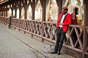 Fashion african american man model at red suit, with highlights hair and handbag posed at street. photo