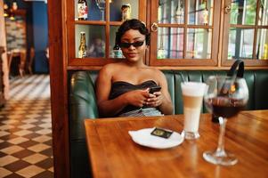 retrato de mujer afroamericana, peinado retro posando en el restaurante con una taza de café con leche. foto