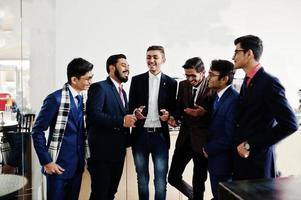 grupo de seis hombres de negocios indios en trajes parados en un café y discutiendo algo. foto