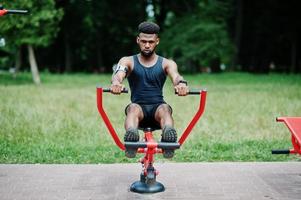 African american male athlete sport man with running sports arm case for mobile phone, doing exercises on the street workout simulators. photo