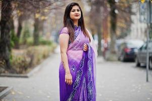 Indian hindu girl at traditional violet saree posed at autumn street. photo