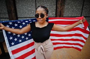 Stylish african american woman in sunglasses posed outdoor with usa flag. photo