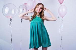chica feliz con vestido verde turquesa con globos de colores aislados en blanco. celebrando el tema del cumpleaños. foto