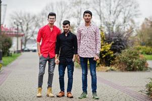 Three indian guys students friends walking on street. photo