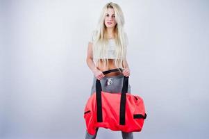 Chica rubia deportiva con una gran bolsa deportiva posada en el estudio con fondo blanco. foto