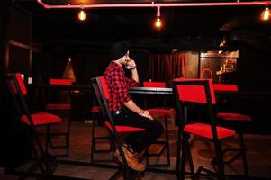 Indian man in checkered shirt and black turban sitting at bar. photo