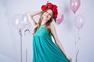 Happy girl in green turqoise dress and wreath with colored balloons isolated on white. Celebrating birthday theme. photo