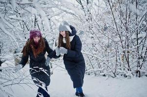 dos amigas divertidas divirtiéndose en el día de invierno cubierto de nieve cerca de árboles cubiertos de nieve. foto