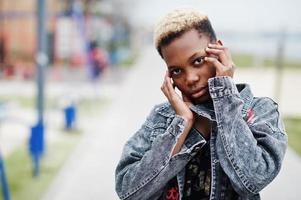 Young millennial african american girl in city. Happy black woman with wireless earphones. Generation Z concept. photo