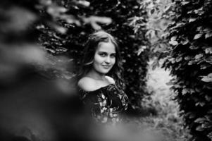 Portrait of a fabulous young girl in pretty dress with stylish curly hairstyle posing in the forest or park. photo