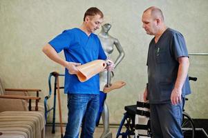 Two prosthetist man workers with prosthetic leg working in laboratory. photo