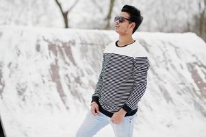 Casual young indian man in sunglasses posed at winter day. photo