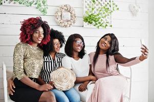 Four best friends. Young adrican women having fun, sitting on the retro couch. photo