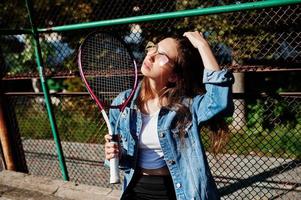 Young sporty girl player with tennis racket on tennis court. photo