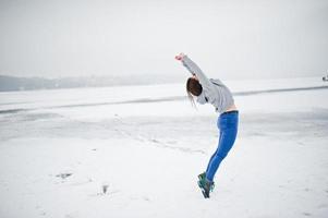 Funny jumping girl on frozen lake in winter day. photo