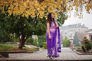 Indian hindu girl at traditional violet saree posed at autumn street. photo