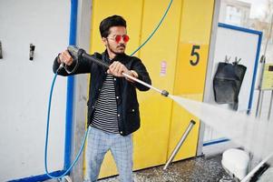 South asian man or indian male washing his white transportation on car wash. photo