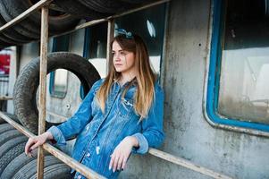 joven hipster con chaqueta de jeans y pañuelo en la cabeza en la zona de montaje de neumáticos. foto