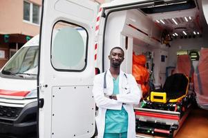 African male paramedic standing in front of ambulance car. photo