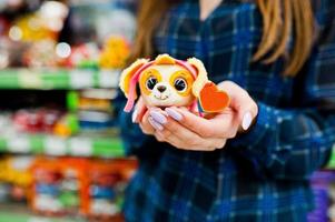 mujer de compras mirando los estantes del supermercado. retrato de una niña en una tienda de mercado con pequeños juguetes blandos. foto