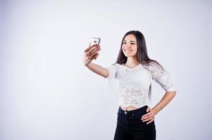 Portrait of a young beautiful woman in white top and black pants taking selfie. photo