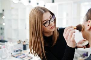 Make up artist work in her beauty visage studio salon. Woman applying by professional make up master. Beauty club concept. photo