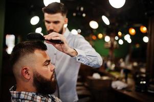 apuesto hombre barbudo en la barbería, peluquero en el trabajo. foto