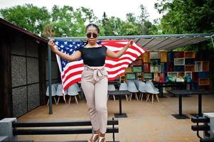 Stylish african american woman in sunglasses posed outdoor with usa flag. photo