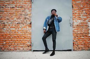 African american man in jeans jacket, beret and eyeglasses, smoking cigar. photo