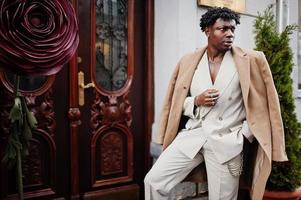 Stylish afro man in beige old school suit and coat. Fashionable young African male in casual jacket on bare torso. photo