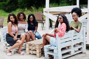 Group of five african american girls relaxing at beach outside cafe. photo