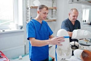 dos trabajadores protésicos que fabrican una pierna protésica mientras trabajan en el laboratorio. foto