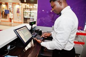 African american bartender at bar uses a calculator on cashier. photo