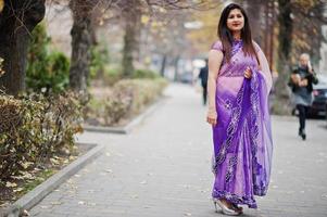 niña hindú india en el sari violeta tradicional posó en la calle otoño. foto