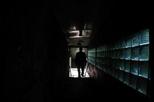Industrial interior of an old abandoned factory. Man in shadow tonnel. Scary concept. photo