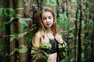 Military girl in camouflage uniform against army background. photo