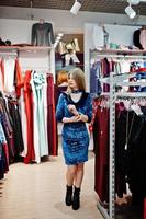 chica rubia con vestido azul en la boutique de la tienda de ropa. foto