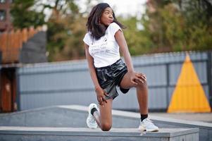 African american dark skinned slim model posed in a black leather shorts and white t-shirt. photo