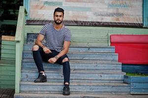 Handsome tall arabian beard man model at stripped shirt posed outdoor. Fashionable arab guy. photo