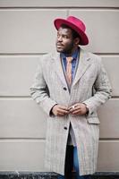 Stylish African American man model in gray coat, jacket tie and red hat. photo