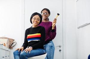 mujer afroamericana aplicando maquillaje por maquillador en el salón de belleza. foto