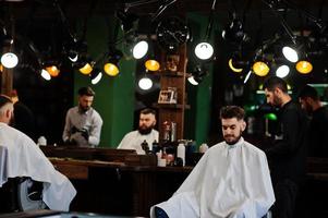 apuesto hombre barbudo en la barbería, peluquero en el trabajo. foto