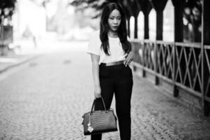 Stylish african american business woman with handbag on streets of city. photo