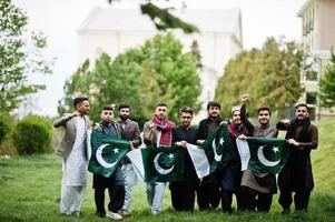 grupo de hombres paquistaníes vestidos con ropa tradicional salwar kameez o kurta con banderas de pakistán. foto