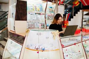 Portrait of young caucasian female woman seller using laptop. Small business of candy souvenirs shop. photo